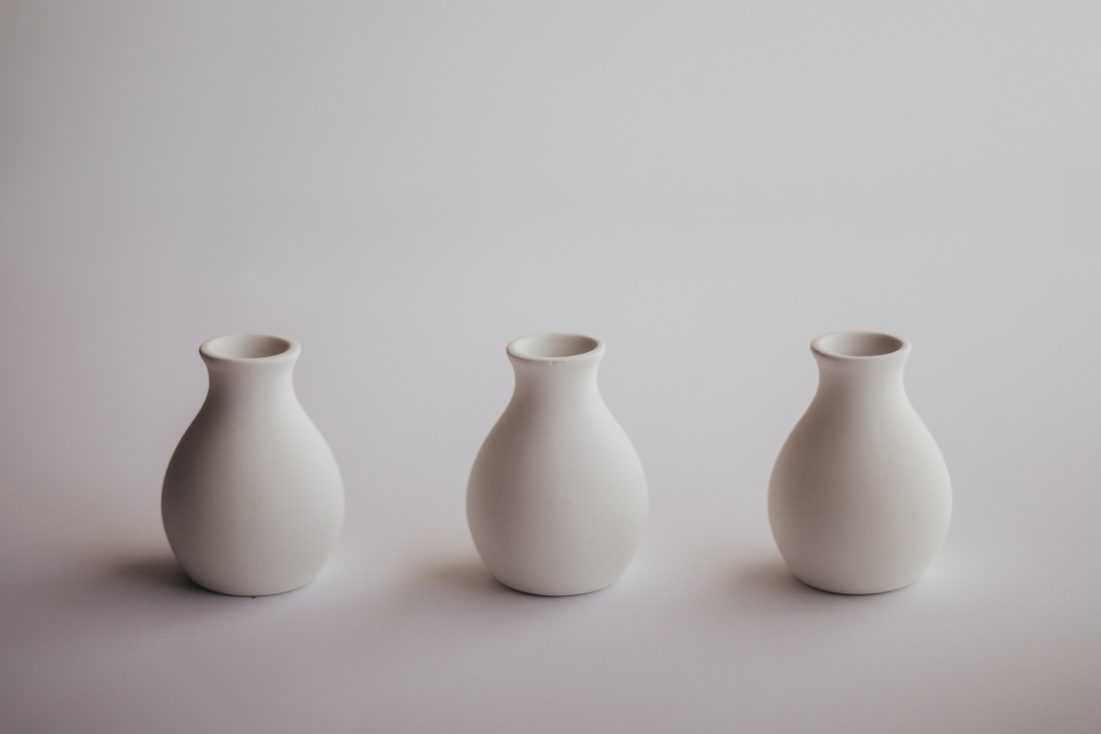 three white vases lined up in a row